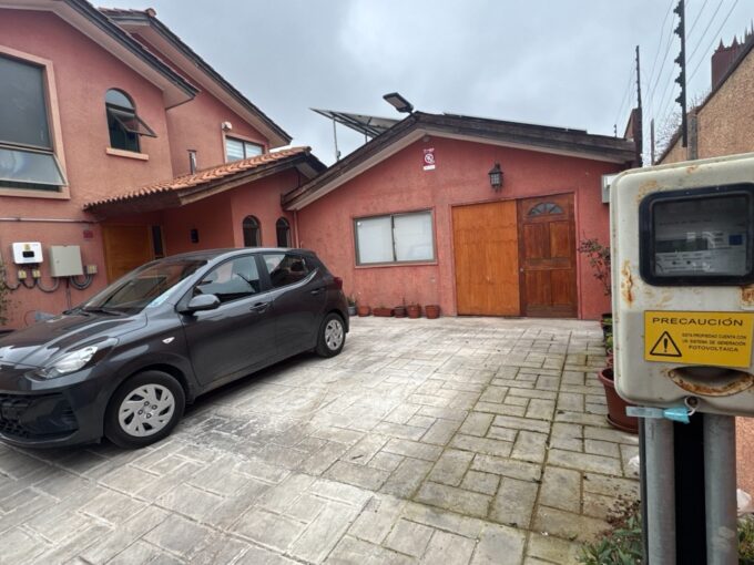 Fachada de casa de color terracota con estacionamiento de piedra